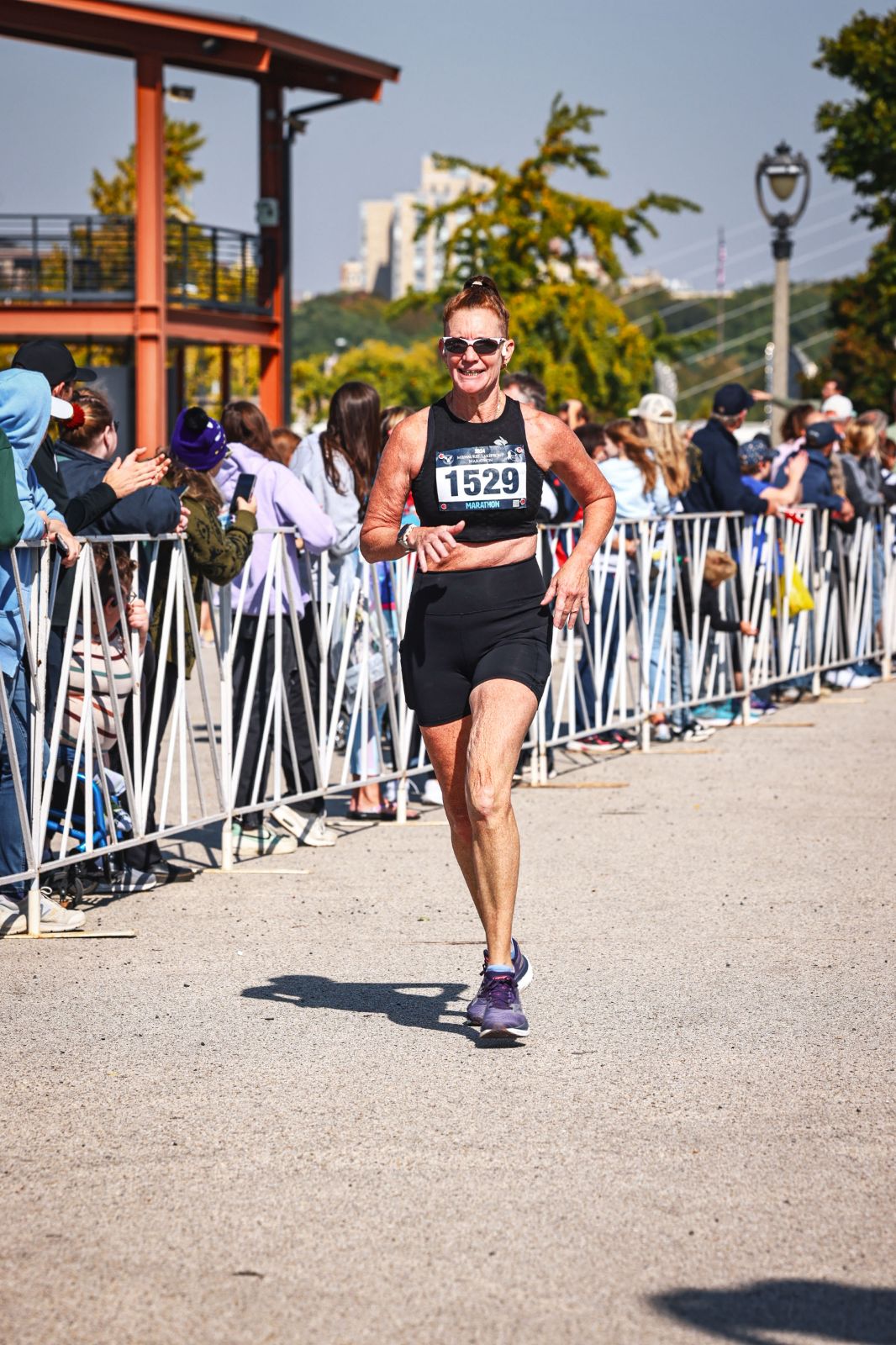 foundational fitness strength training coach runs to the marathon finish line with a smile.